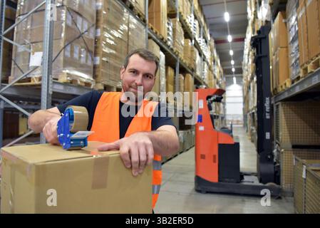 Arbeiter in einem Warenlager im Einzelhandel verpackten ein Paket mit Klebeband Stockfoto