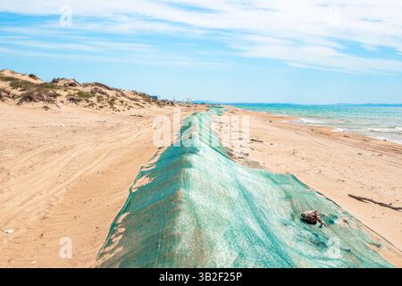 Öl ist im Meer verschüttet. Barriere-Sanddüne, bedeckt mit Schutznetz vor Heizöl, das von Wellen an Land geworfen wird. Ökologische Katastrophe, Methoden der Elim Stockfoto