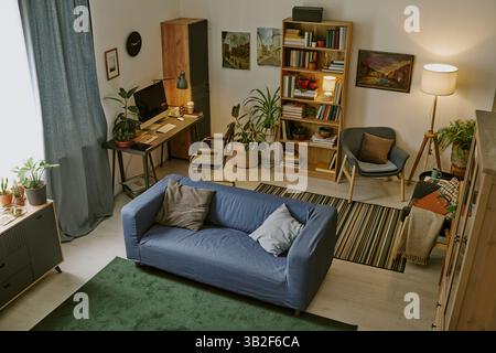 Hochwinkelaufnahme der großen Arbeitszone mit Holzmöbeln und einer großen Anzahl von Büchern auf Regalen im modernen Wohnzimmer Stockfoto