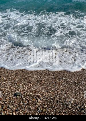 Meereswelle mit weißem Schaum über einem Kiesstrand in Antalya, Türkei. Stockfoto