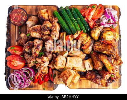 Auf einer lebendigen Platte gibt es eine Auswahl an gegrilltem Fleisch und frischem Gemüse. Saftige Hähnchenflügel, herzhaftes Schweinefleisch und bunte Tomaten sorgen für einen Stockfoto