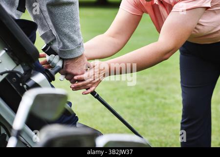 Golfplatz, Hände- und Coach-Unterricht im Club, Feld oder im Freien, um beim Unterricht zu helfen. Golfspieler, Lehrer oder Menschen mit Behinderung, die halten lernen Stockfoto