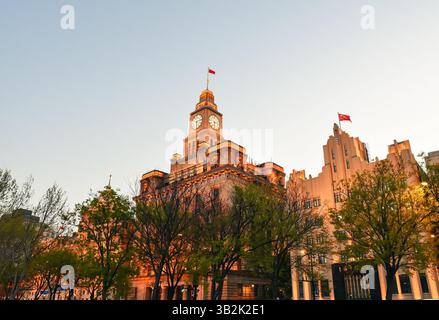 Shanghai, China - 1. April 2025: Der Bund bei Sonnenuntergang mit dem historischen Shanghai Customs House und dem Art Deco AIA Building, das vor goldenem Himmel leuchtet Stockfoto
