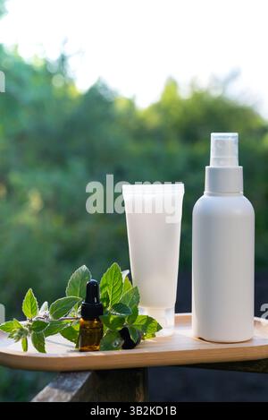 Weiße handgemachte Kosmetikflaschen Vorlage Mockup Hautpflege Kräuter Alternative Insektenschutz draußen im Sommer. Versuche, Mücken und Fliegen mit organischen Inhaltsstoffen Minzextraktöl zu töten. Prophylaxe-Desinfektion gegen Mückenstich an sonnigen Tagen. Stockfoto