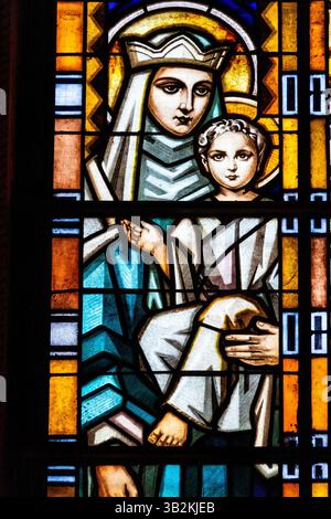 Ribadesella, Spanien - 26. April 2025: Glasmalerei der Heiligen Jungfrau Maria, die das Baby Jesus Christus in ihren Armen hält. Stockfoto
