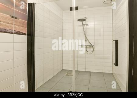Eine elegante und moderne Duschkabine mit gefliesten Wänden und minimalistischem Design schafft einen erfrischenden Badebereich, der Funktionalität und Stil kombiniert. Stockfoto