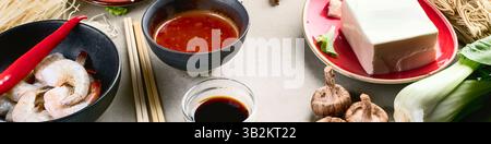 Asiatisches Essenskonzept. Zutaten: Garnelen, Salat, Pilze, Gewürze auf grauem Hintergrund von oben. Chinesische und thailändische Küche. Panorama. Stockfoto