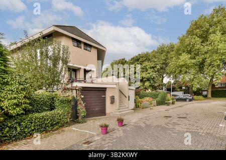 Ein modernes Haus mit einem gepflegten Garten und einer Auffahrt, in einem ruhigen Vorstadtviertel mit üppigem Grün gelegen. Stockfoto