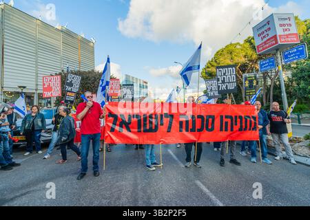 Haifa, Israel - 26. April 2025: Menschen mit verschiedenen Schildern und Flaggen nehmen an einer Protestkundgebung Teil, die die Beendigung des Krieges und die Vollendung der Geiselnahme fordert Stockfoto