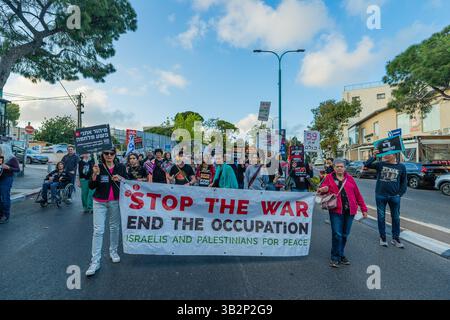Haifa, Israel - 26. April 2025: Menschen nehmen an einem protestmarsch (Friedensaktivistengruppe) Teil, mit verschiedenen Zeichen und Fahnen, die zum Ende des Krieges aufrufen Stockfoto