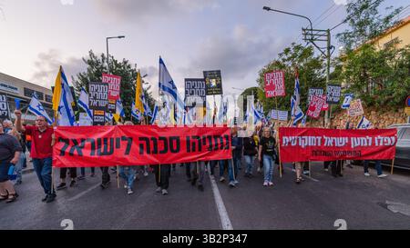 Haifa, Israel - 26. April 2025: Menschen mit verschiedenen Schildern und Flaggen nehmen an einer Protestkundgebung Teil, die die Beendigung des Krieges und die Vollendung der Geiselnahme fordert Stockfoto