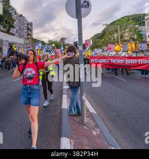 Haifa, Israel - 26. April 2025: Menschen mit verschiedenen Schildern und Flaggen nehmen an einer Protestkundgebung Teil, die die Beendigung des Krieges und die Vollendung der Geiselnahme fordert Stockfoto