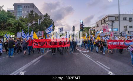 Haifa, Israel - 26. April 2025: Menschen mit verschiedenen Schildern und Flaggen nehmen an einer Protestkundgebung Teil, die die Beendigung des Krieges und die Vollendung der Geiselnahme fordert Stockfoto