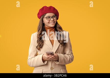 Bloggerin für Mädchen nutzt das Smartphone. Surfen im Internet und Bloggen. Chatten und SMS schreiben. Teenager-Mädchen-Chat online isoliert auf gelb. Herbst-STYLE. Teenager Stockfoto