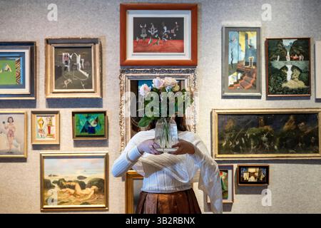 London, Großbritannien. 28. April 2025. Ein Angestellter mit Rosen vor Grundstücken zum Verkauf bei einer Vorschau auf Bonhams British Surrealisalism Sale in Bonhams New Bond Street Galeries. Der Verkauf läuft online bis zum 1. Mai. Quelle: Stephen Chung / Alamy Live News Stockfoto