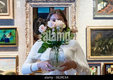 London, Großbritannien. 28. April 2025. Ein Angestellter mit Rosen vor Grundstücken zum Verkauf bei einer Vorschau auf Bonhams British Surrealisalism Sale in Bonhams New Bond Street Galeries. Der Verkauf läuft online bis zum 1. Mai. Quelle: Stephen Chung / Alamy Live News Stockfoto