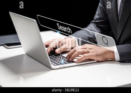 Geschäftsmann, der Hand auf einem Laptop mit dem Symbol einer Online-Suchmaschine schreibt. Technologische Innovation auf einem virtuellen Bildschirm. Konzept der SEO, Suche Stockfoto