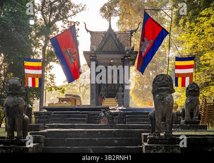 Ein ruhiger Tempeleingang mit Fahnen, Steinlöwenstatuen und üppigem Grün im Hintergrund. Das warme Licht erzeugt ein friedliches atmos Stockfoto