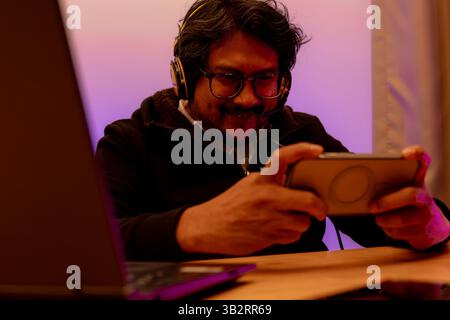 Glücklicher asiatischer Mann, Gamer, spielen Videospiele online mit Smartphone Stockfoto