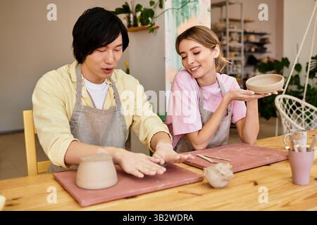 Das junge Paar bastelt gern gemeinsam Töpferwaren, teilt Lachen und Kreativität im Studio. Stockfoto