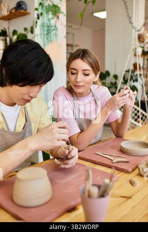 In einem hellen Töpferstudio bastelt ein junges Paar Töpferwaren und teilt Lächeln und Kreativität. Stockfoto