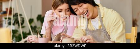 Ein junges Paar bastelt zusammen Keramik und lacht in einer fröhlichen Studiosession. Stockfoto