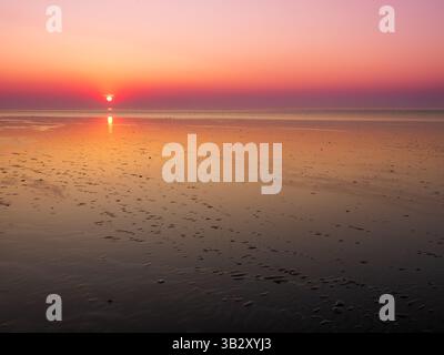 Weitläufige Gezeitenebenen bei Ebbe vor der Küste Frieslands, Niederlande, Sonnenuntergang über ruhigen UNESCO-Feuchtgebieten im Wattenmeer Stockfoto