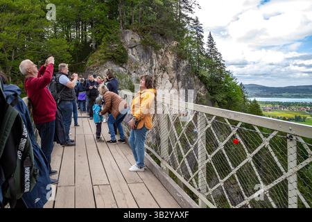 SCHWANGAU, DEUTSCHLAND - 23. MAI 2024: Unbekannte Touristen machen Fotos auf der Maria-Brücke über die Pellatschlucht, die atemberaubende Ausblicke bietet. Stockfoto