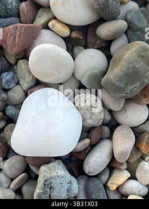 Makrofoto von farbenfrohen, glatten Kieselsteinen mit einem großen weißen Stein im Fokus Stockfoto