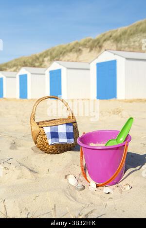 Zeile blau-weißen Strand Hütten, Spielzeug und Picknick-Korb Stockfoto