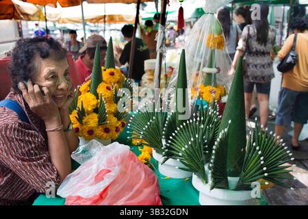 Mai 2015 - Bangkok, Thailand - Blumenverkäuferin in Pak Khlong Talat, Blumenmarkt, Bangkok, Thailand. Pak Khlong Talat ist ein Markt in Bangkok, Thailand, der Blumen, Obst und Gemüse verkauft. Es ist der wichtigste Blumenmarkt in Bangkok und wurde für die Einwohner Bangkoks als „Ort der symbolischen Werte“ bezeichnet. Es liegt an der Chak Phet Road und angrenzenden Seitenstraßen, in der Nähe der Memorial Bridge. Obwohl der Markt rund um die Uhr geöffnet ist, ist er vor Sonnenaufgang am meisten beschäftigt, wenn Boote und LKW mit Blumen aus den nahe gelegenen Provinzen ankommen. Der Markt hat eine lange Geschichte. Während der Regierungszeit von Rama I. ( Stockfoto