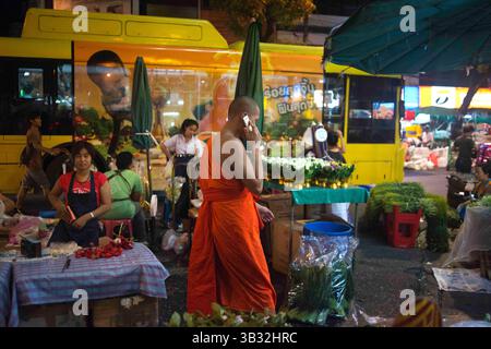 Dezember 2015 - Bangkok, Thailand - Mönch bei Nacht in Pak Khlong Talat, Blumenmarkt, Bangkok, Thailand. Pak Khlong Talat ist ein Markt in Bangkok, Thailand, der Blumen, Obst und Gemüse verkauft. Es ist der wichtigste Blumenmarkt in Bangkok und wurde für die Einwohner Bangkoks als „Ort der symbolischen Werte“ bezeichnet. Es liegt an der Chak Phet Road und angrenzenden Seitenstraßen, in der Nähe der Memorial Bridge. Obwohl der Markt rund um die Uhr geöffnet ist, ist er vor Sonnenaufgang am meisten beschäftigt, wenn Boote und LKW mit Blumen aus den nahe gelegenen Provinzen ankommen. Der Markt hat eine lange Geschichte. Während der Regierungszeit von Rama I. (1782–1809) Stockfoto