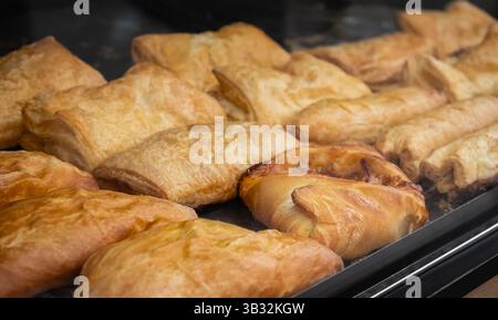 Konditorei zum Verkauf. Frisch gebackenes Blätterteiggebäck in einem Regal der Bäckerei. Gebäck mit verschiedenen Füllungen. Selektiver Fokus, niemand Stockfoto