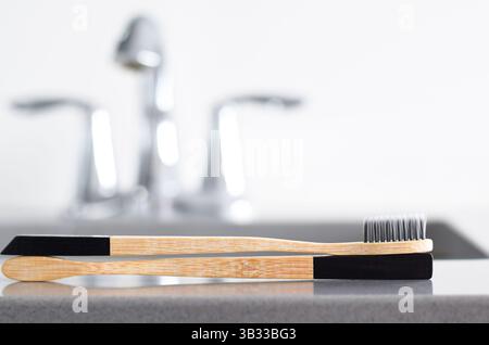 Zwei umweltfreundliche Holzzahnbürsten aus Bambus auf der Theke im Badezimmer mit Kopierraum Stockfoto