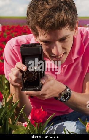 Portrait von Ayoung Mann Fotografieren in Tulpen Feld mit alten Vintage-Kamera Stockfoto