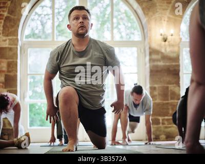 Yoga, Klasse und Mann im Fitnessstudio zu trainieren, Fitness und gesunden Körper für ganzheitliche Wellness. Ernsthafte Person, Club und Übung Pilates mit einer Gruppe von Menschen Stockfoto