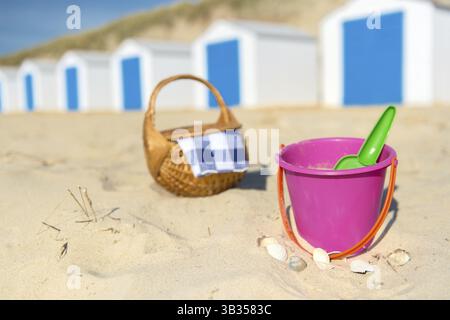Zeile blau-weißen Strand Hütten, Spielzeug und Picknick-Korb Stockfoto