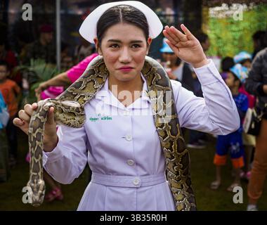 13. Januar 2018 – Bangkok, Thailand – Eine thailändische Krankenschwester grüßt während der Aktivitäten zum Kindertag im 2. Kavallerie-Lager der Königsgarde der Royal Thai Army im Zentrum von Bangkok, während sie eine Python hält. Der Kindertag wird auf Thailändisch „Wan DEK“ genannt. Viele Regierungsbüros und Militärbasen bieten spezielle Aktivitäten für Kinder an, ebenso wie Einkaufszentren. (Kreditbild: © Sean Edison via ZUMA Wire) Stockfoto