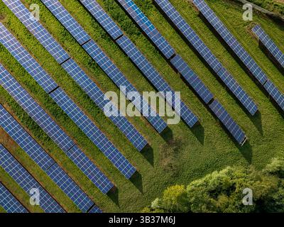 Reihen von Photovoltaik-Solarpaneelen auf landwirtschaftlichen Flächen, die saubere, nachhaltige Energie für Geschäfts- und Haushaltszwecke erzeugen Stockfoto
