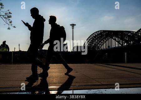 Silhouetten von Menschen mit Handys in der Hand, im späten Sonnenlicht, am Deutzer Ufer, am rechten Rheinufer, an der Rhein-prome Stockfoto
