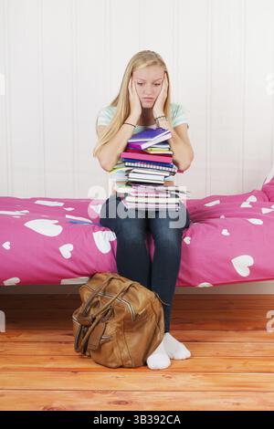 Vierzehn Jahre altes Mädchen mit vielen Schulbüchern und zu viele Hausaufgaben Stockfoto