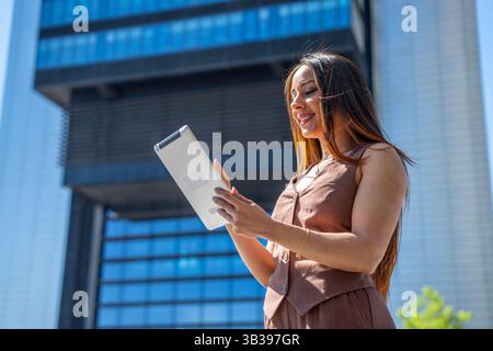 Lächelnde Geschäftsfrau mit digitalem Tablet vor dem Bürogebäude Stockfoto