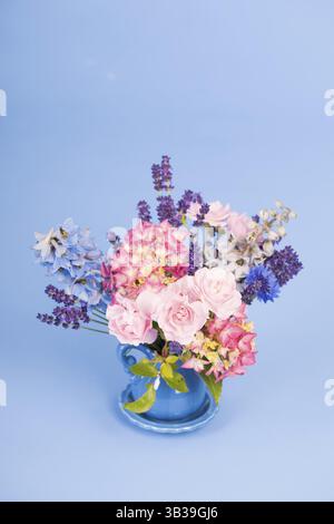 Bunter Strauß Blumen in Vase auf blauem Hintergrund Stockfoto
