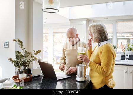Zuhause, Lächeln und Laptop mit Seniorenpaar, Liebe und Ruhestand mit Verbindung, Gesundheit und Internet. Wohnung, alter Mann und ältere Frau mit pc Stockfoto