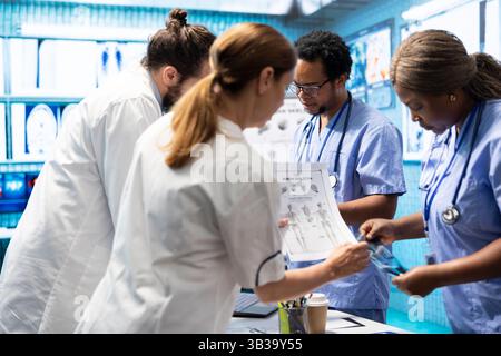 Das Healthcare-Team diskutiert menschliche Anatomie und diagnostische Strategien in einer medizinischen Praxis. Durch die kollektive Arbeit werden genaue Behandlungspläne und professionelle Lösungen sowie Fachkenntnisse in der Radiologie sichergestellt. Stockfoto