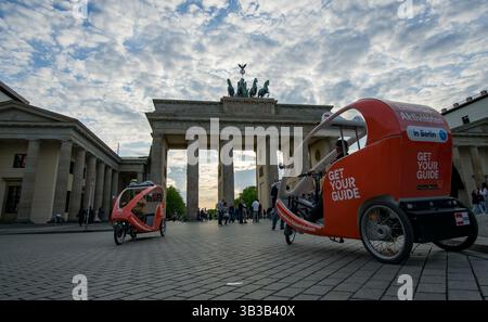 Vor dem Brandenburger Tor in Berlin warten moderne Rikschas mit Marken auf Touristen, die geführte Stadtführungen und Besichtigungserlebnisse anbieten. Stockfoto