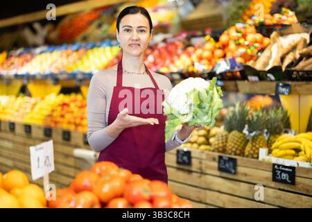 Weibliche Lebensmittelläden bieten Reifen Brokkoli-Kohl in der Lebensmittelabteilung des Supermarktes an Stockfoto