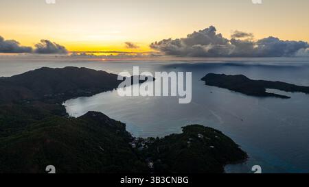 Goldenes Sonnenlicht erstreckt sich über das ruhige Meereswasser und beleuchtet die umliegenden Inseln. Stockfoto