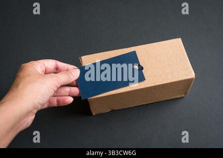 Händige ein blaues Etikett auf das Papppaket. Kopierbereich. Stockfoto
