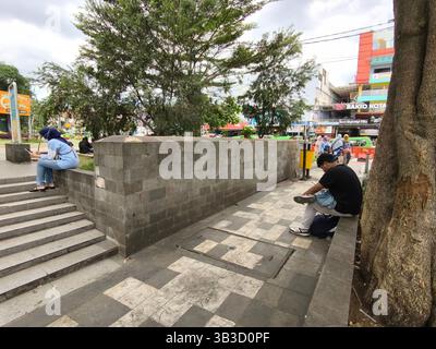 Zwei Personen, die mit ihren Handys auf dem Bogor City Square beschäftigt sind Stockfoto